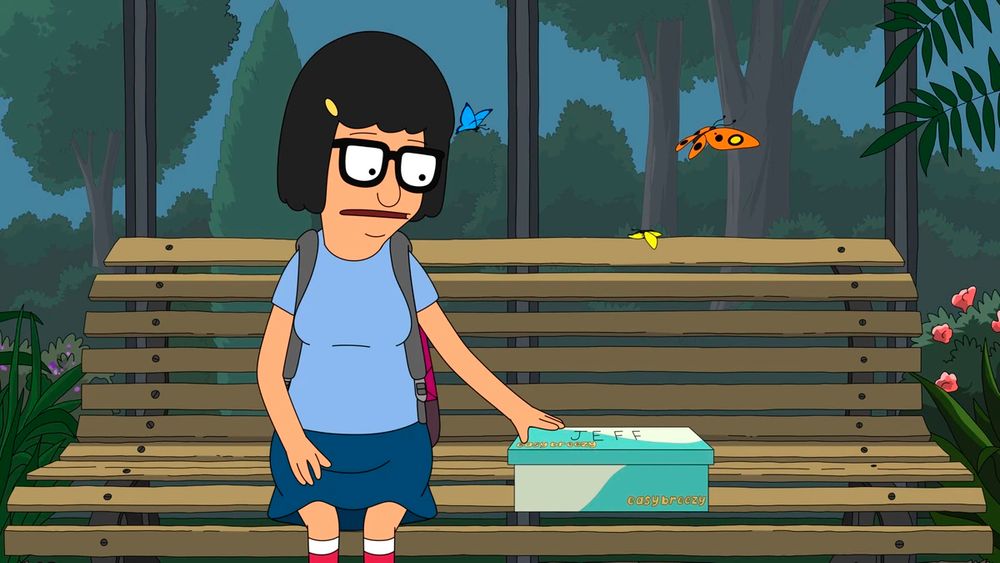 Tina sits on a bench with a shoebox 