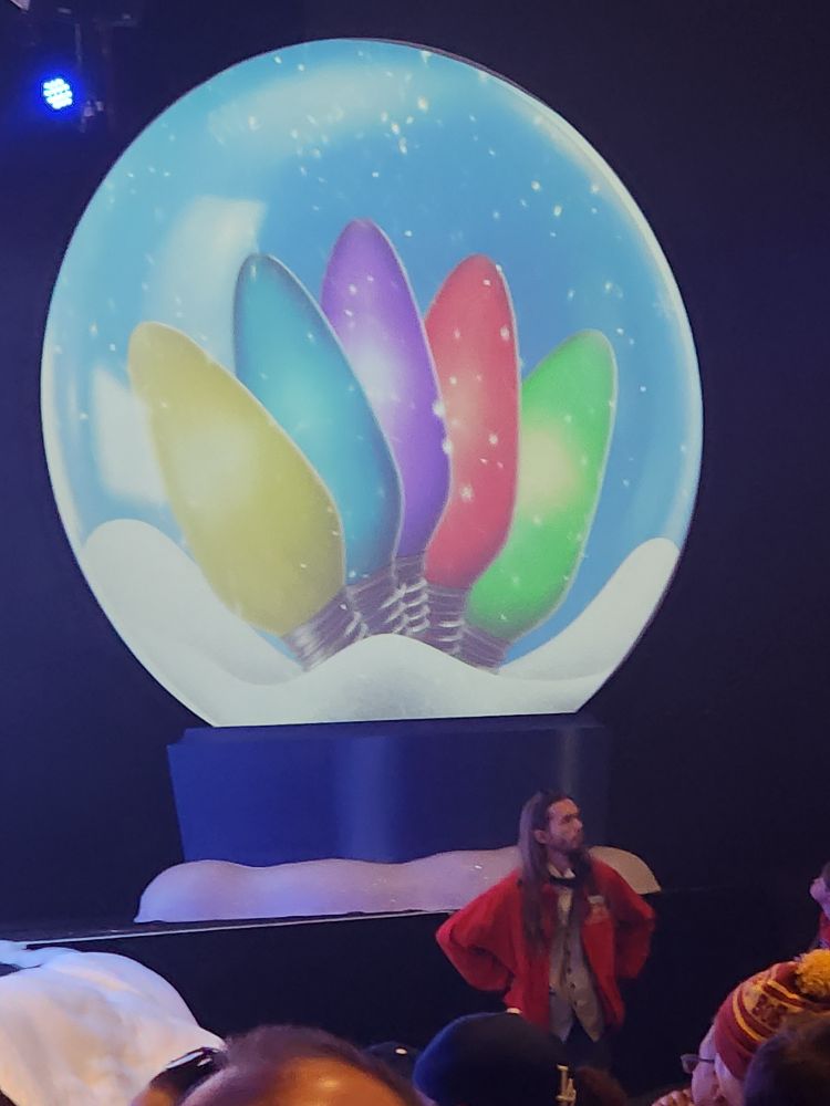 A snowglobe with five Christmas lights - yellow, blue, black, red and gree, arranged in that order