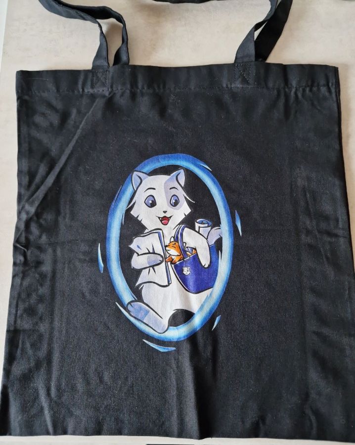 Black tote bag with a cat leaving a blue portal carrying various kinds of merch.