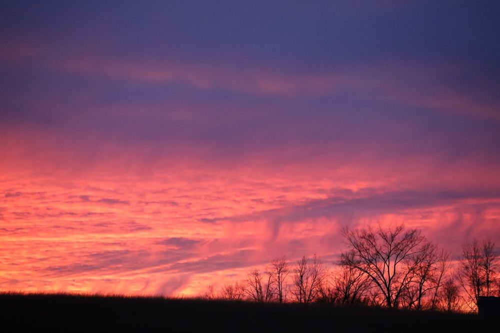 Soft pink sunset with purple clouds above, the shape of the clouds look like gentle waterfalls