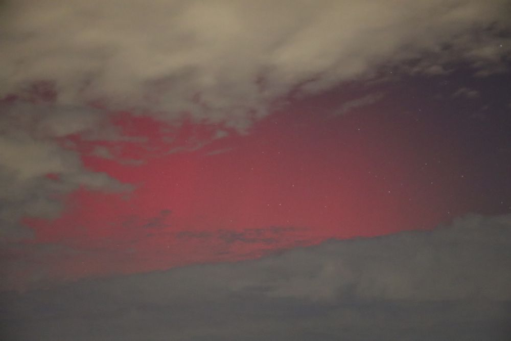 Close-up of the pink pillars peeking through a hole in the clouds. You can also see the stars, shining through the lights. 