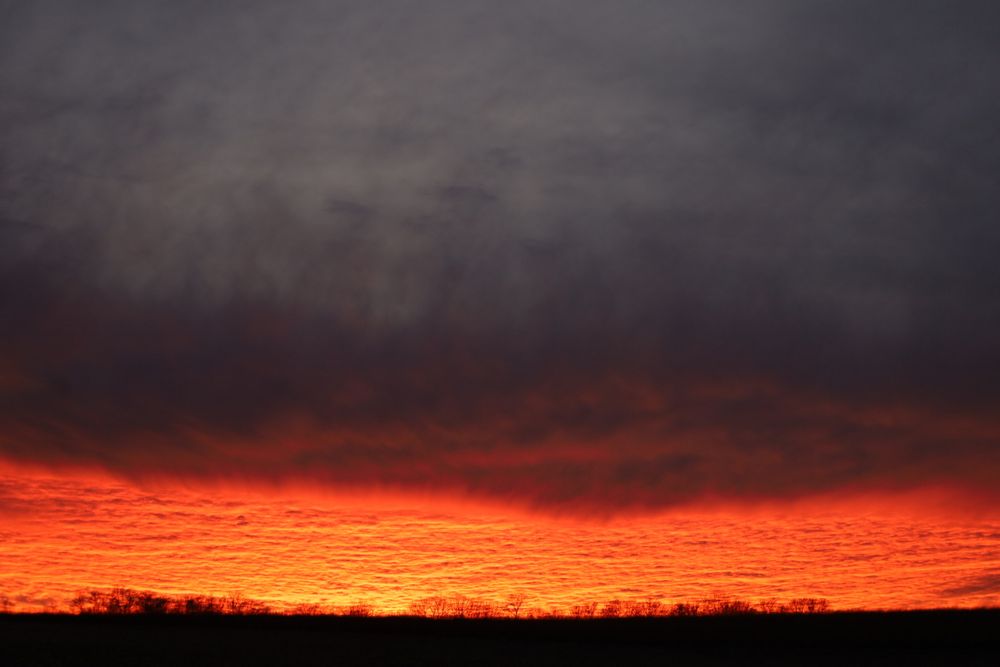 Dark heavy clouds lit from below by a bright orange sky, almost like lava