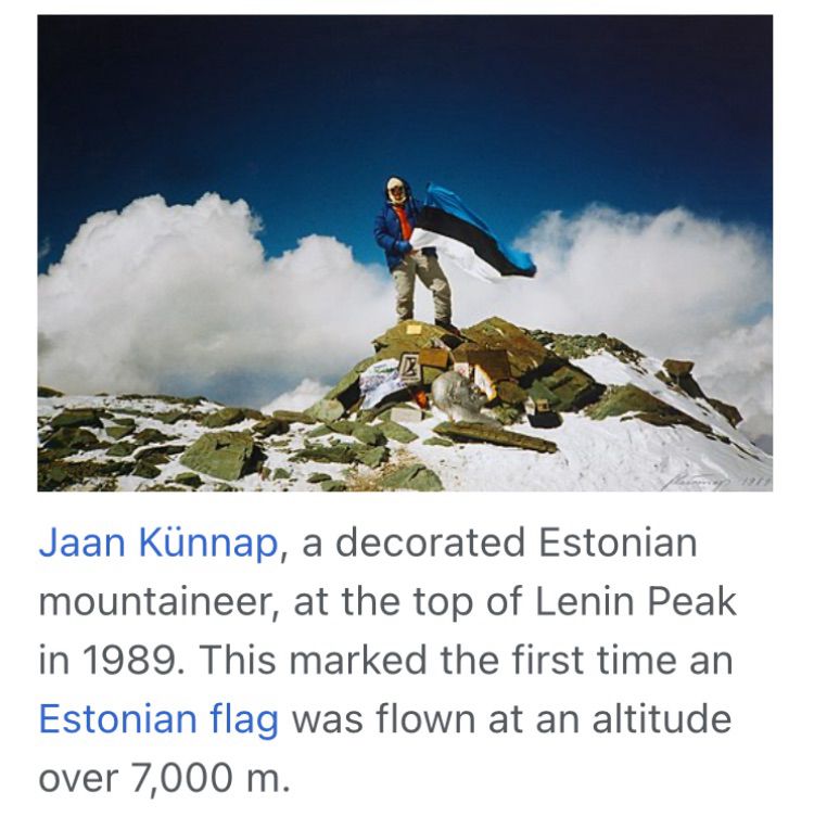 Screenshot from the Wikipedia article about Lenin Peak, showing a mountaineer at the top of the peak waving a blue, black, and white striped flag. The caption reads: Jaan Künnap, a decorated Estonian mountaineer, at the top of Lenin Peak in 1989. This marked the first time an Estonian flag was flown at an altitude over 7,000 m.