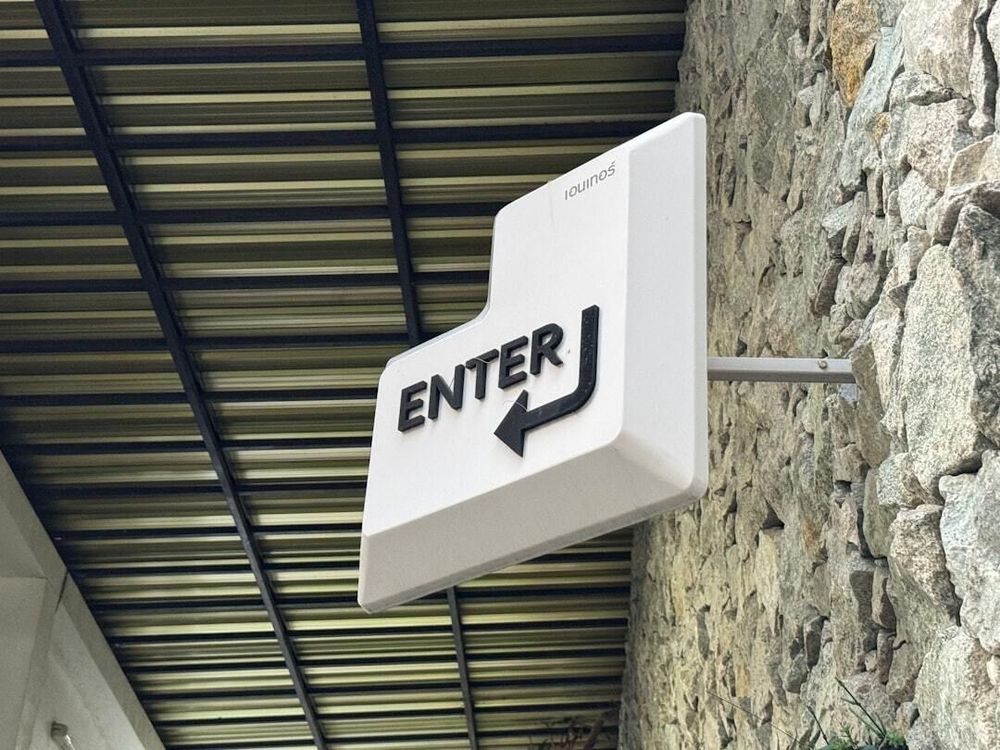 A mounted white sign in the shape of an "enter" key from a keyboard.