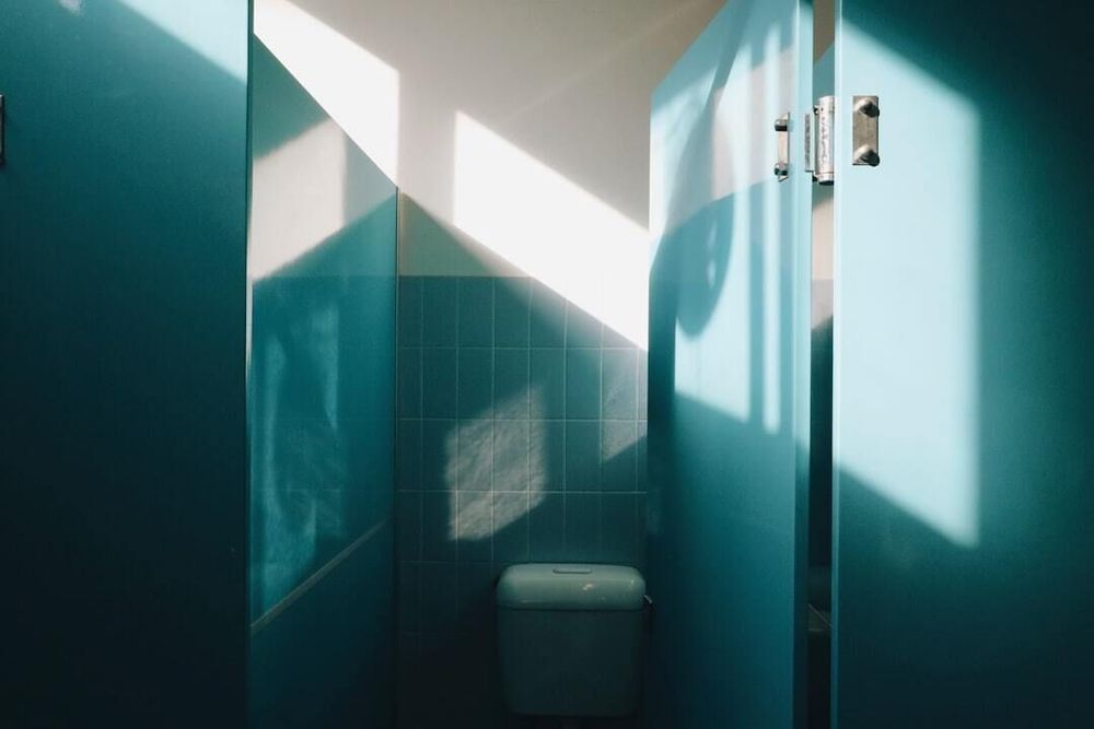A blue bathroom stall with the door open.