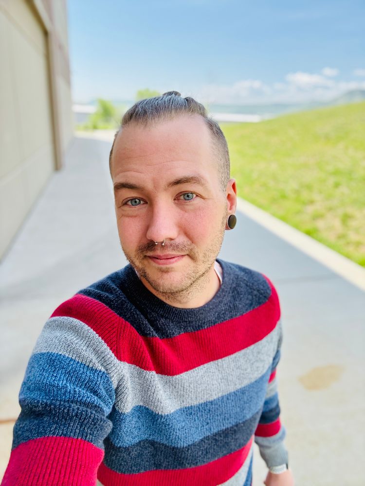 Selfie of cortland walking outside. Grass and blue sky in the background.