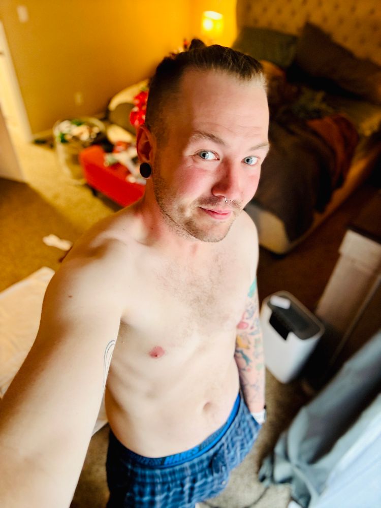 Shirtless selfie of cortland wearing blue plaid pajama pants.