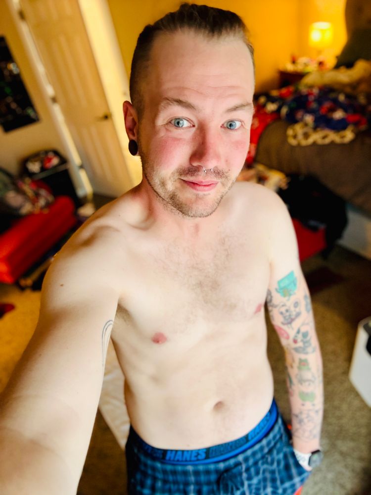 Shirtless selfie of cortland wearing blue plaid pajama pants.