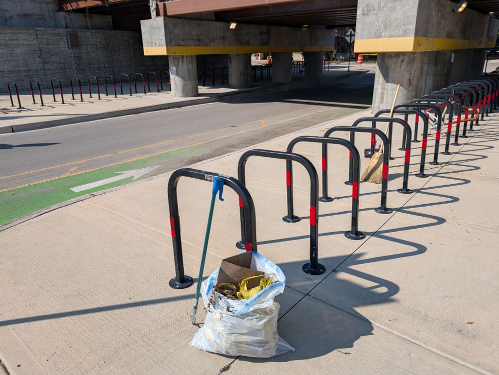 A trash bag full of litter in front of bicycle racks.