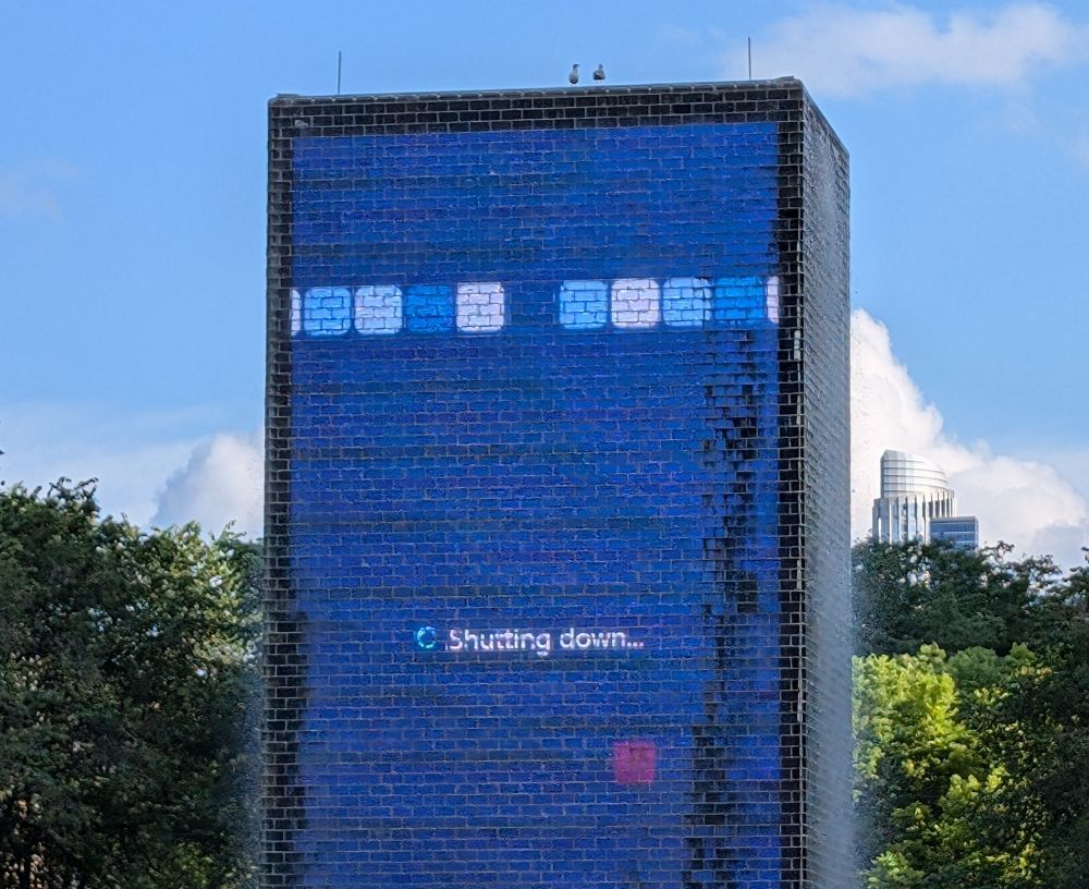 A building size screen projects a "Shutting Down" screen from the Windows operating system.