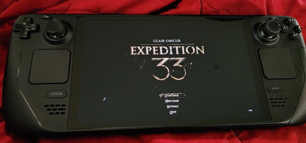 A photo of a steamdeck featuring the main menu of Clair Obscur Expedition 33