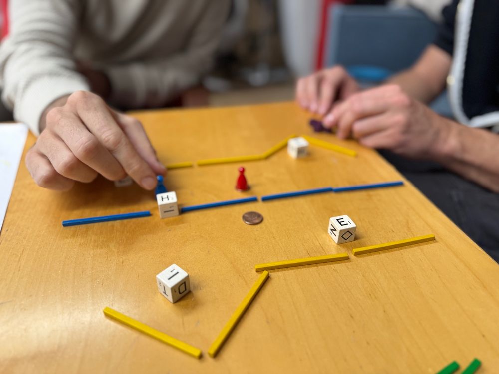 A table with board-game pieces. Kevin and Jan's hands interacting with them.