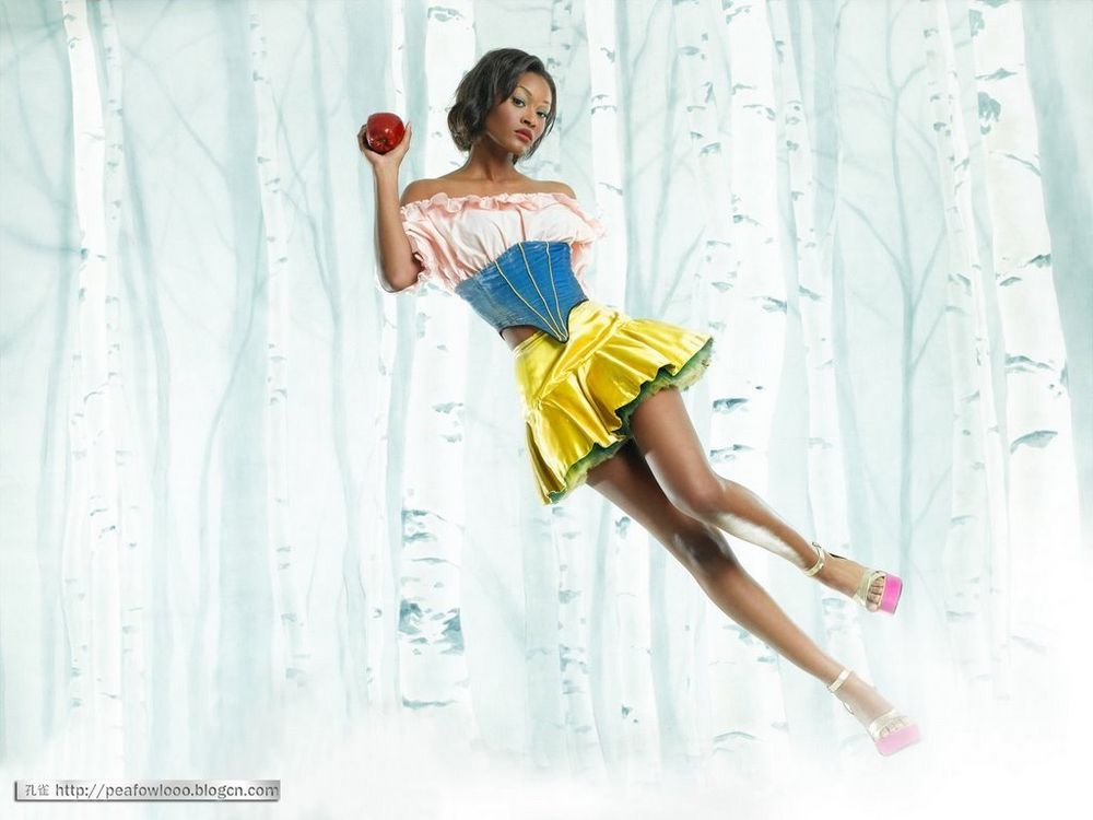 Danielle Evans from ANTM season 6. She is dressed in a modern, stylized Snow White outfit. She wears a pink off-the-shoulder blouse, a blue corset, and a shiny yellow skirt, holding a red apple in her right hand. 