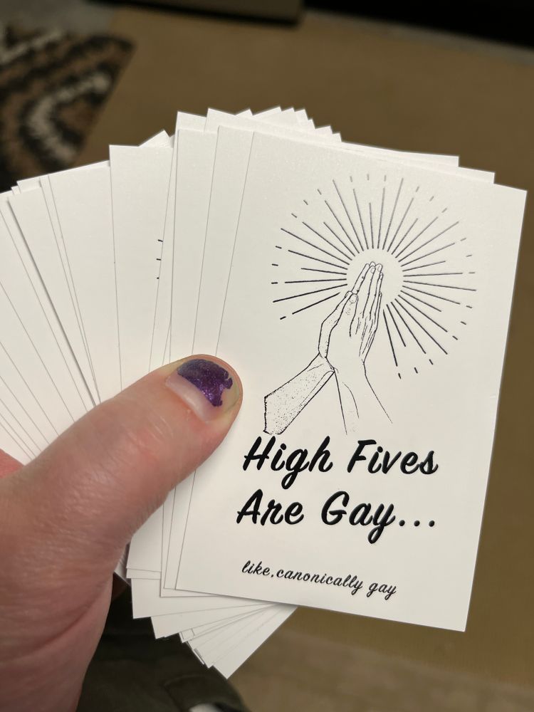 stickers showing two hands touching/slapping that say "High Fives Are Gay... like, canonically gay"