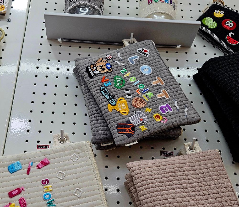 회색 퀼팅 파우치에 롯데 자이언츠 관련 자수 패치들이 빼곡히 붙어 진열되어 있다.
