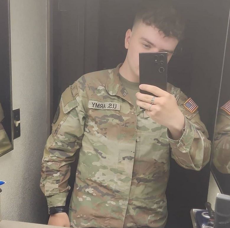 A selfie posted to the facebook page of Cameron Wagenius shows him holding the phone up in front of a mirror, with the phone partially obscuring his face. He is dressed in U.S. military fatigues with a "US Army" patch.