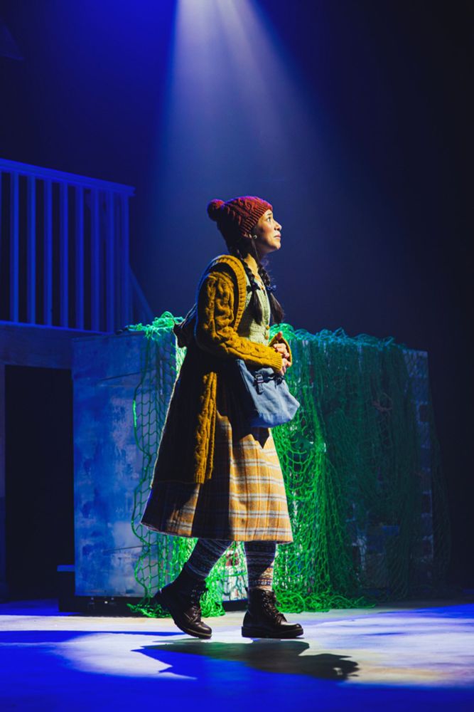 long shot of gerda's whole outfit, she has a pom pom hat, cute skirt, and sensible boots