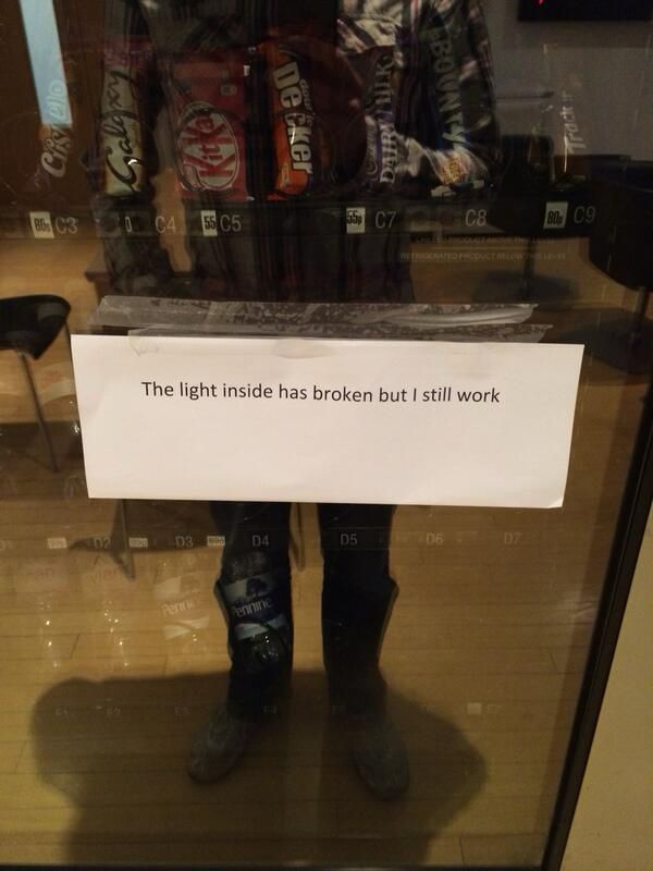 A vending machine with a printed note saying “The light inside has broken but I still work” 