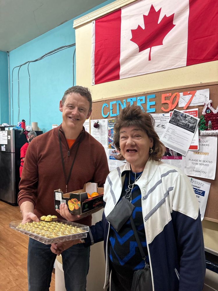 Joel with a neighbour at Centre 507, holding chocolates and oranges