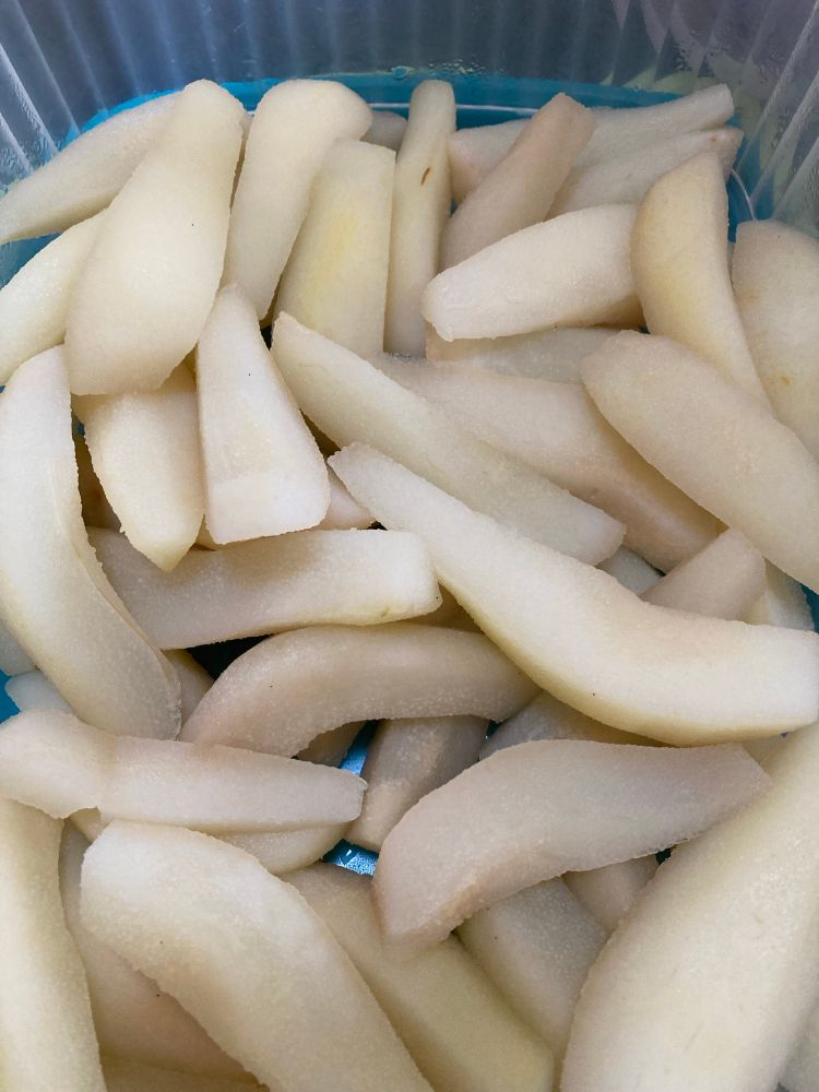 Container full of poached pears, quartered lengthways
