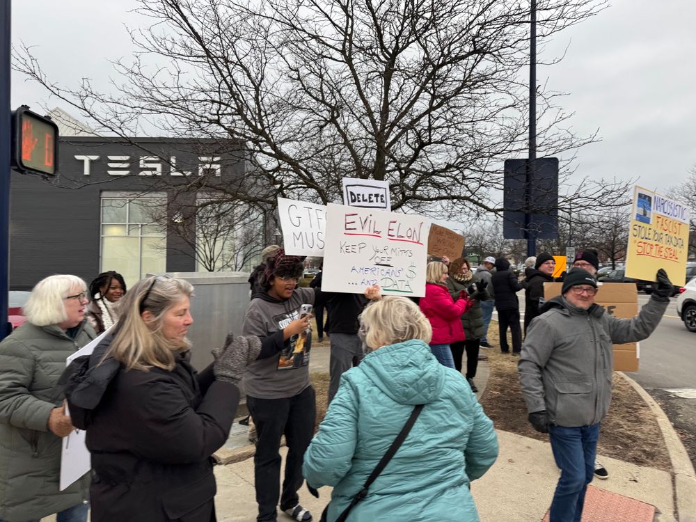 Protestors outside the Easton Tesla store in Columbus, Ohio, on the afternoon of Feb. 9, 2025. Signs read, “GTFO Musk” and “Evil Elon Keep Your Mitts Off American’s $ … and Data!”