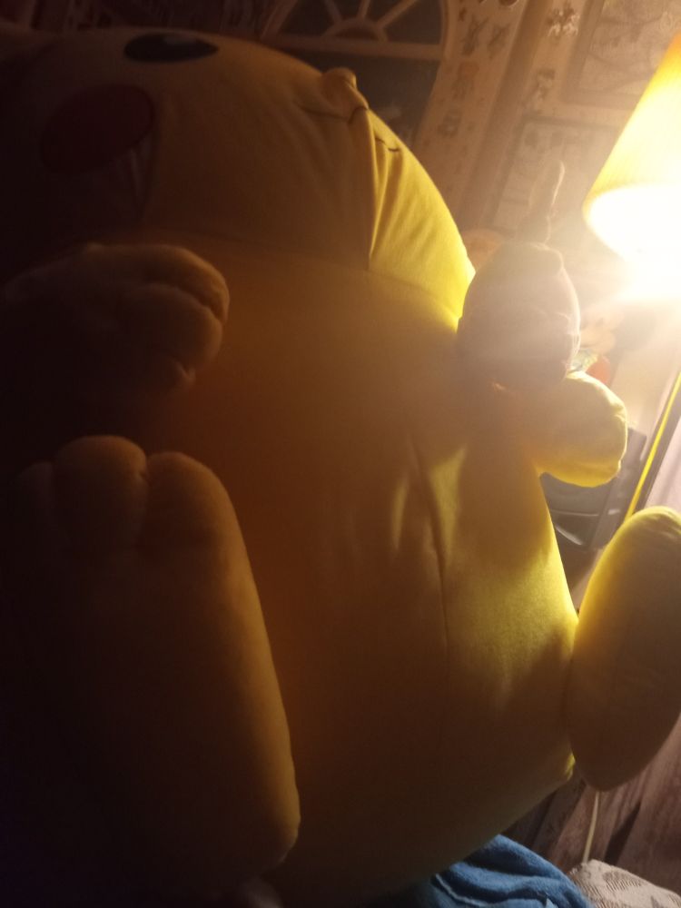 GIANT Carnival type Pikachu plush my dad found at the thrift store, sitting on his couch. He knew I would love it, and I do. OG Happiny plush on its arm for scale.