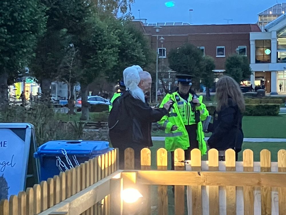 Man with a small white dog on his shoulders talking to police 
