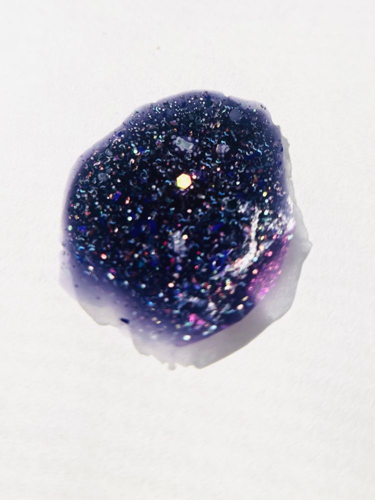 A dried dollop of MOONRISE OVER SUNSET BLVD, a midnight purple to pale violet color-changing nail polish with silver holographic glitters, rainbow glitters, and purple and platinum shreds. This photo shows the polish in its cold state, so it is almost navy in its depth.