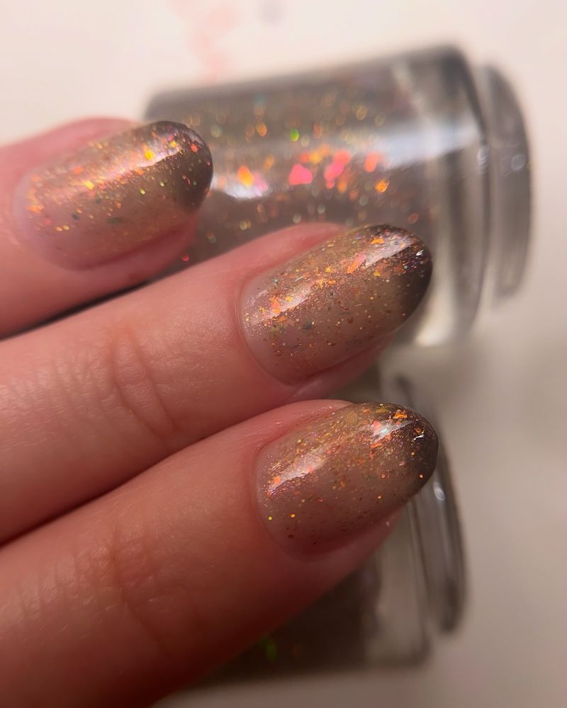 CALIFORNIA CHAPARRAL is a charity polish from Toadistry Lacquer that shifts from opalescent taupe when warm to chocolate brown when cold. This photo shows a common stage of the polish: warmed from body heat but cooled at the tips by ambient air. You can also see the large 15mL round bottles.