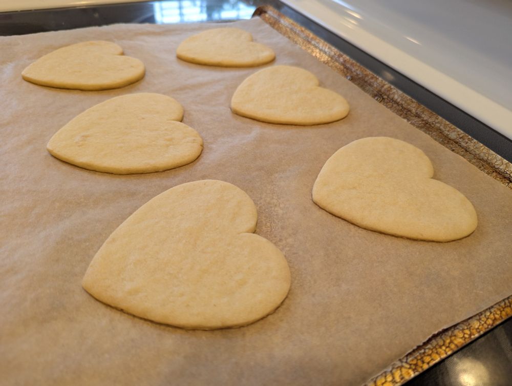 Heart shaped sugar cookies on a cookie sheet lined with parchment paper. Not decorated. 