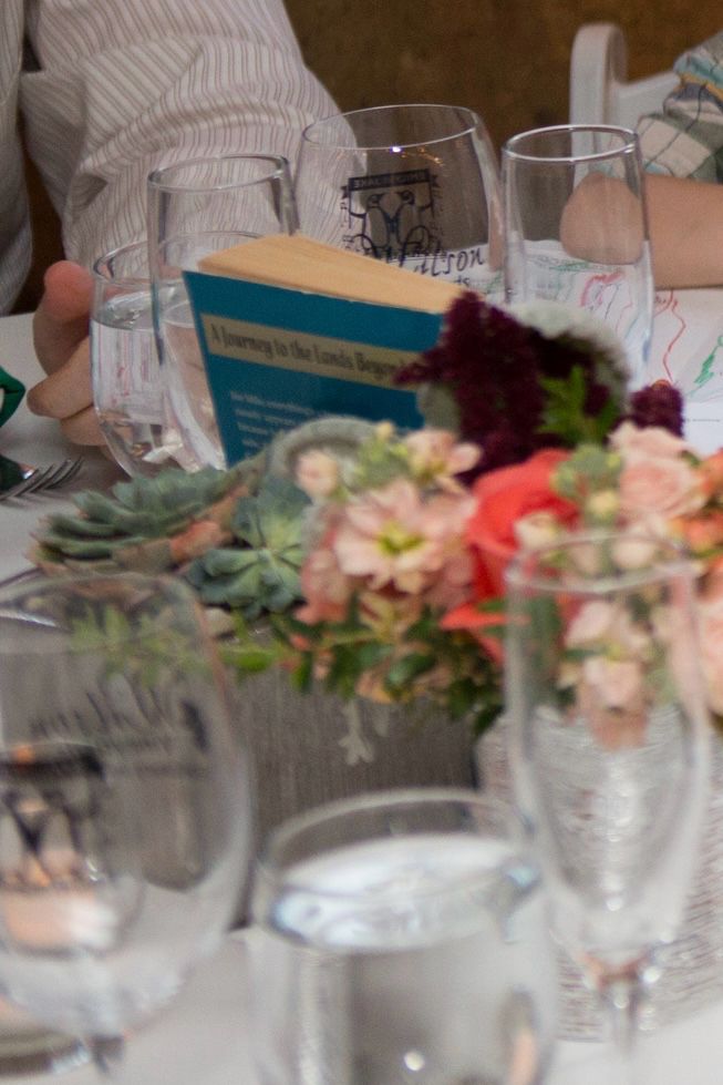 A copy of “The Phantom Tollbooth" by Norton Juster (ill. by Jules Fieffer) in a wedding table centerpiece, surrounded by flowers and dinnerware.
