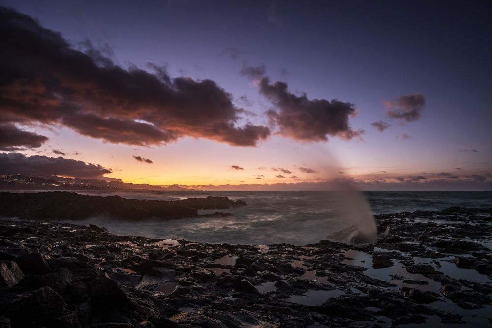 Dusk with rocks and ocean and a blowhole