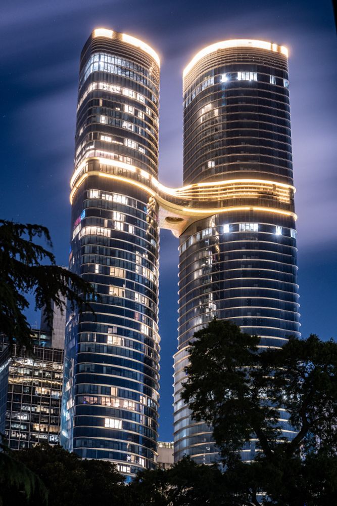 Photograph of twin building at night connected by sky bridge