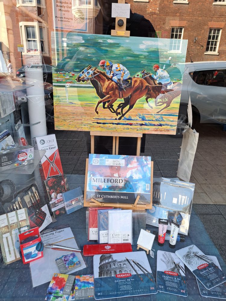 Window of art supplies shop with horseracing painting in acrylics