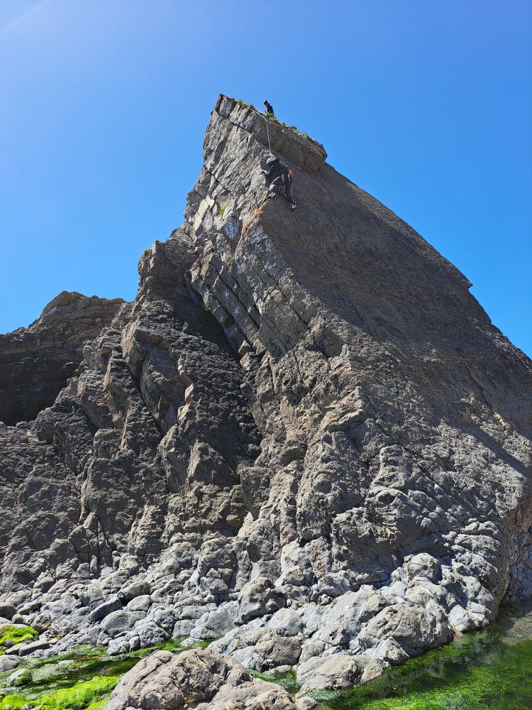 Tilted rock formation with climbers on it