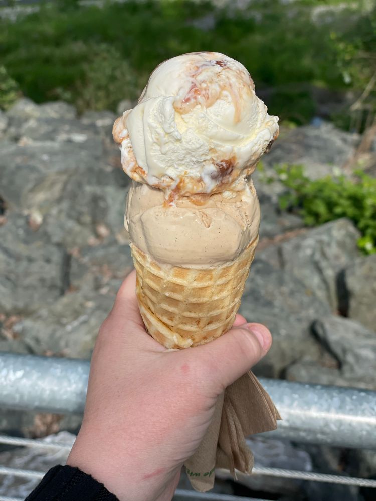 Photo of a hand holding an ice cream cone with two scoops of ice cream. 