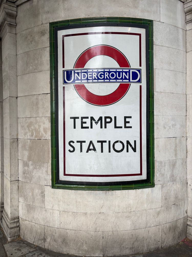 A curved enamel sign reading “Temple Station” located on the corner of the building.