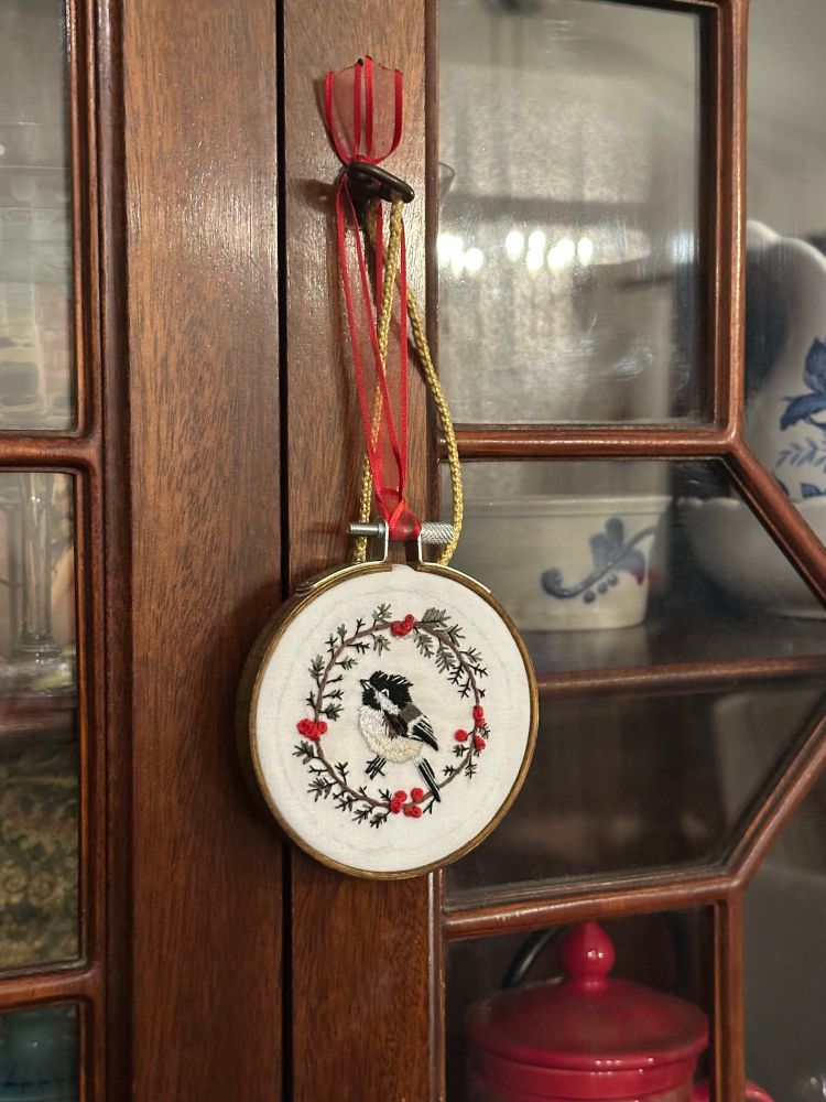 Hand embroidered bird in hoop hanging from ribbon