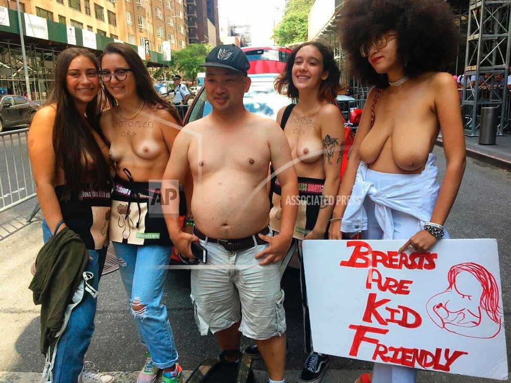 Shirtless people in NY with a sign: Breasts Are Kid Friendly 