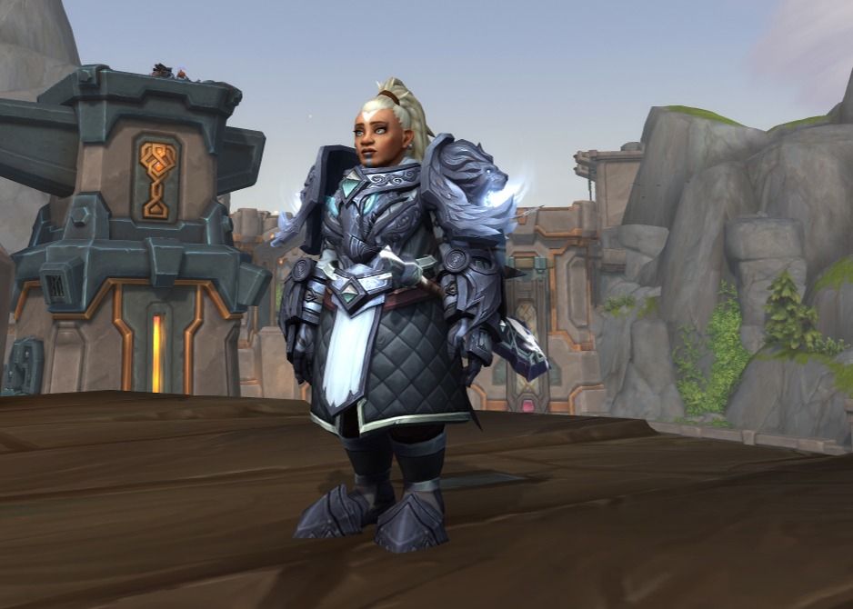 An World of Warcraft in-game screenshot. It shows a lady dwarf paladin in a white and dark grey outfit, with a theme of lions and dragons. 
