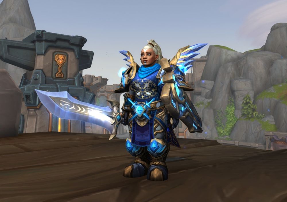 An World of Warcraft in-game screenshot. It shows a lady dwarf paladin in a blue and gold outfit, which is most the now unobtainable Mist of Pandaria Challenge Mode transmog. 
