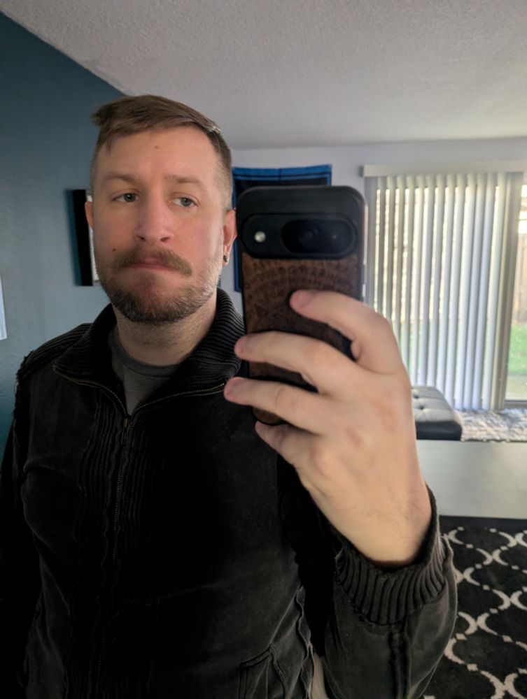 Selfie wearing a grey T-shirt and grey woven jacket.