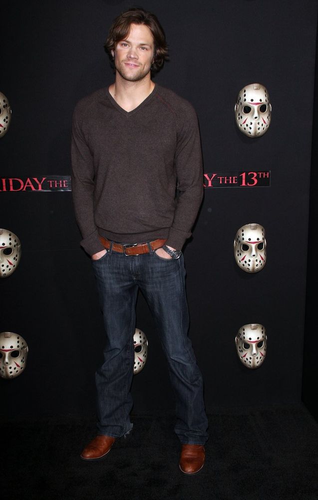 Photo of Jared Padalecki, who is wearing a brown sweater, blue jeans, and brown boots, at the movie premiere of Friday the 13th.