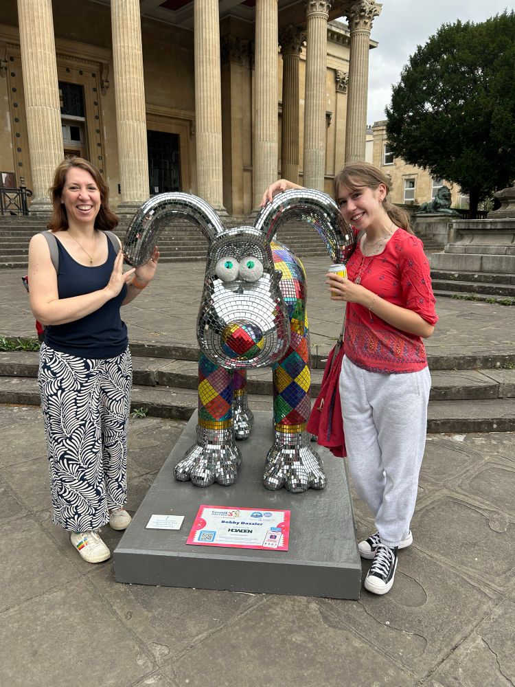 Photo of Tabitha and a teenage girl standing next to a Gromit model like a mirror ball.