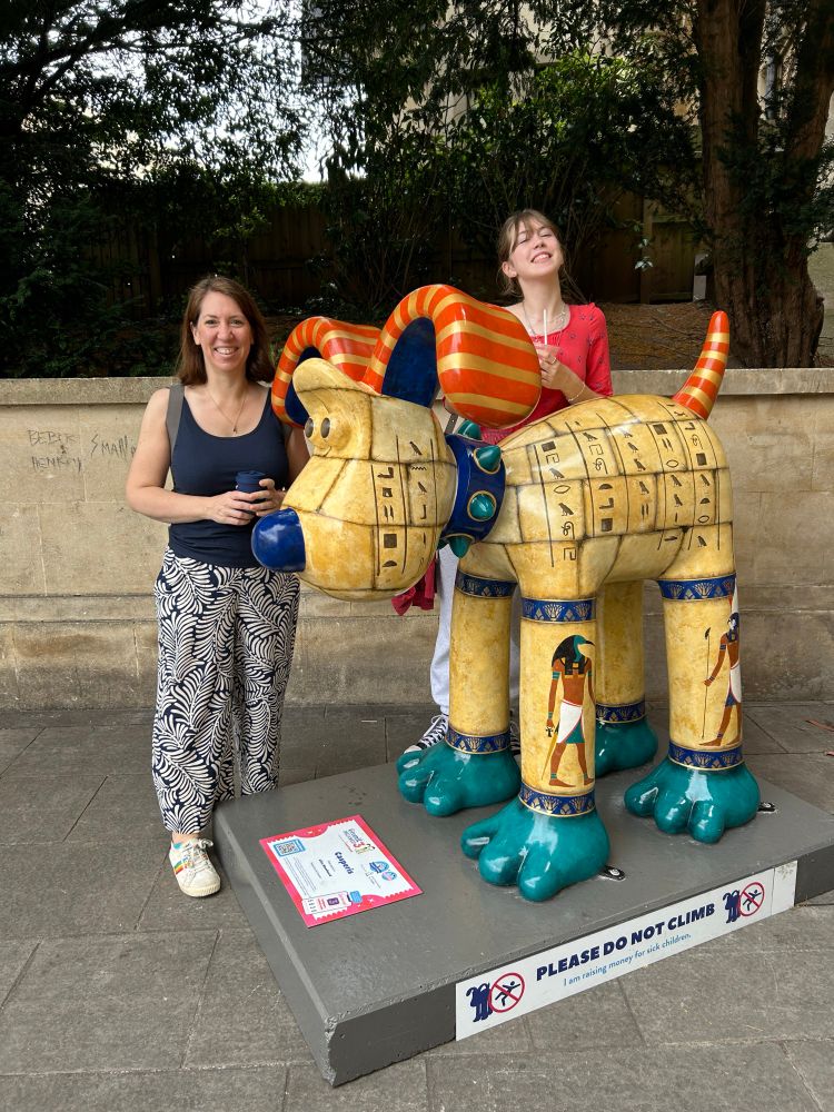 Photo of Tabitha and a teenage girl standing next to a Gromit model painted with hieroglyphics. 