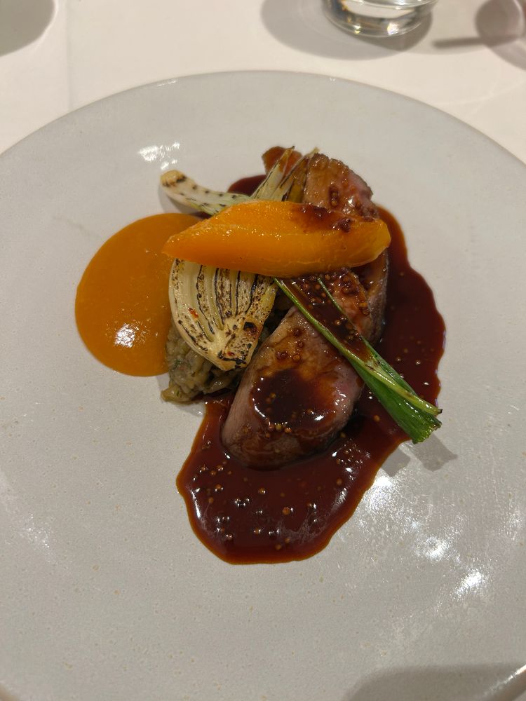 Photo of a main course of Iberico pork chop with an apricot jus and dark grain mustard.