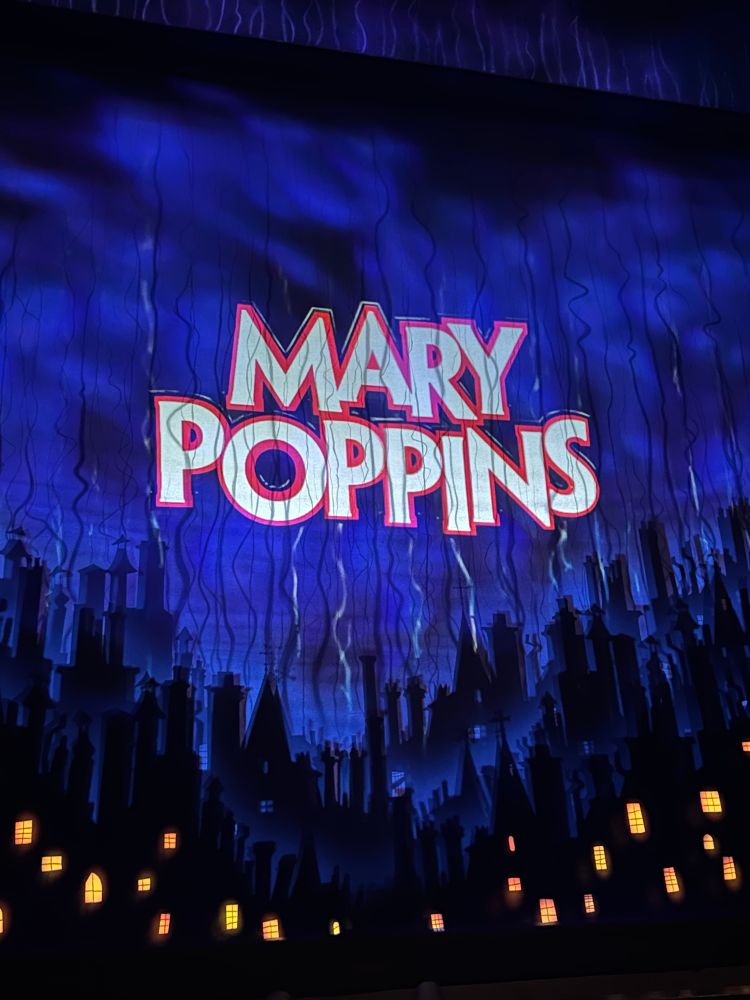 A photo of the holding screen before the show starts. It is a scene of London rooftops by night.