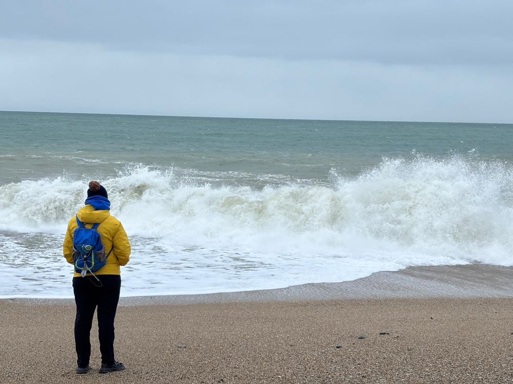Photo of Emily standing by the waves crashing on the shore.