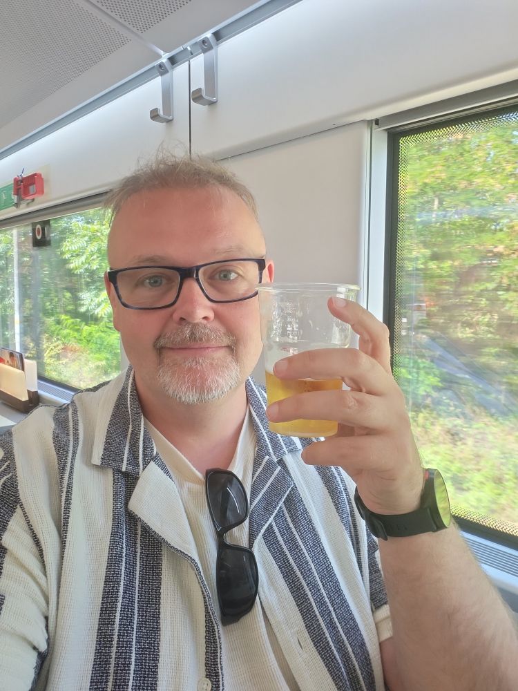 Me, raising a plastic cup of beer to the camera in a train restaurant car somewhere between Como and Milan