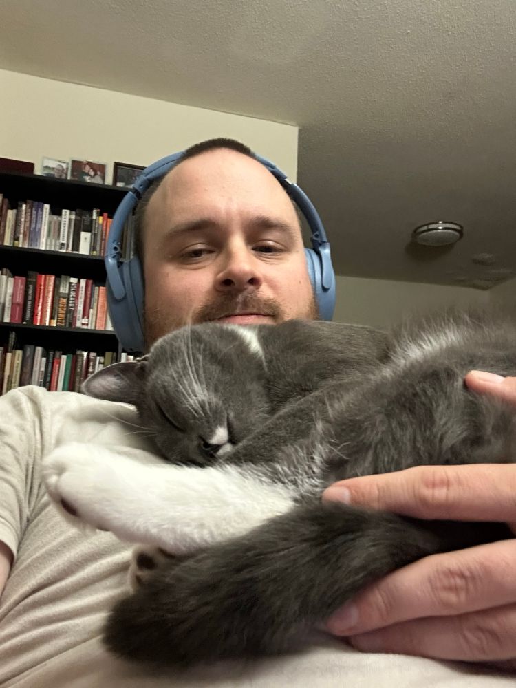 Steele, a gray tuxedo cat with a white mustache, sleeps on my chest